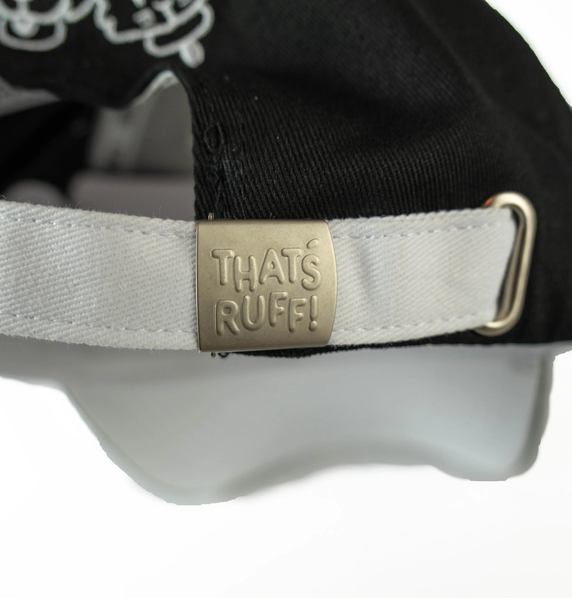 Adjustable black-and-white strapback cap with metal THAT'S RUFF logo clasp—embroidered accessory for furry merch & furry clothing fans.