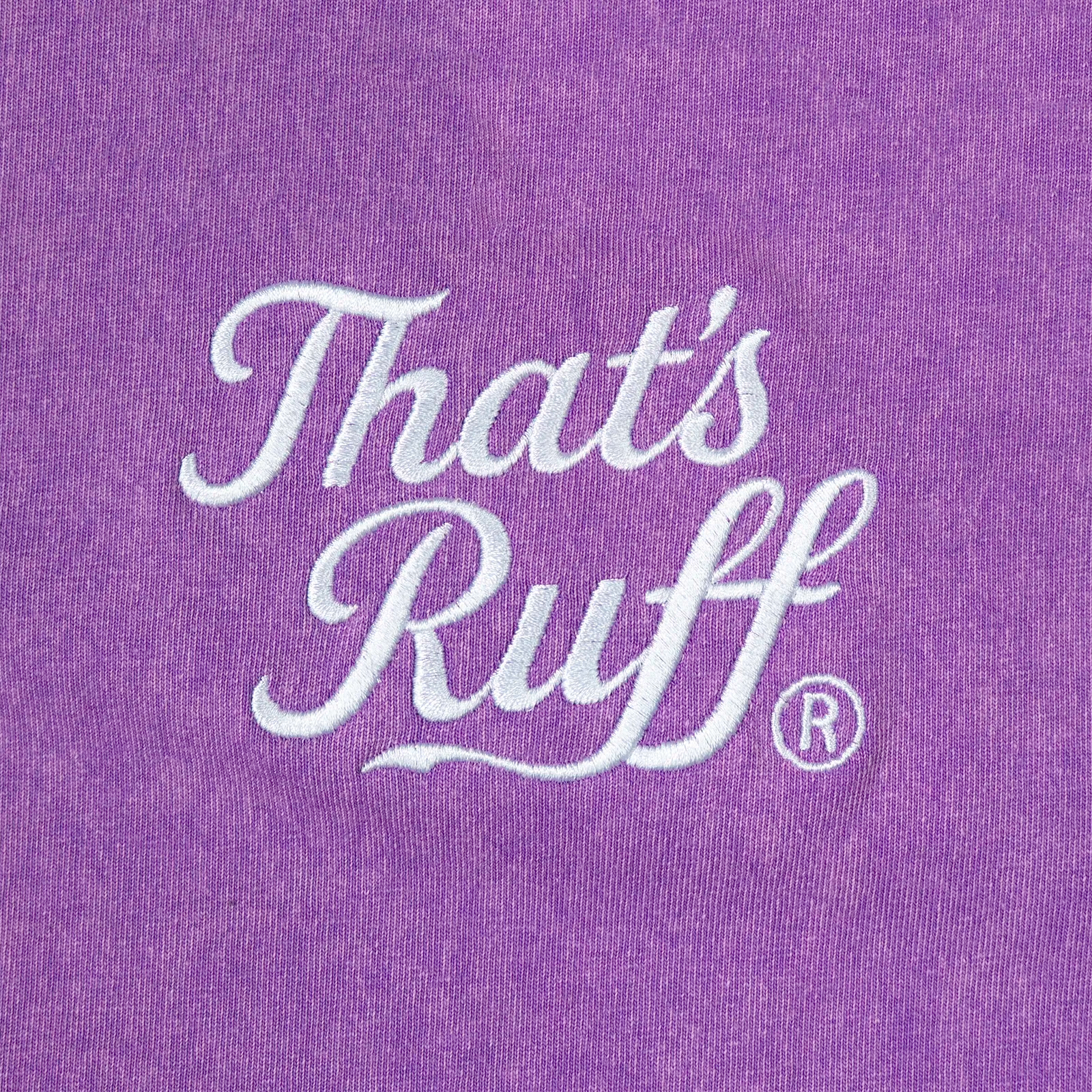 Back-neck embroidery detail showing THAT'S RUFF logo on a washed purple oversized tee—furry apparel/furry clothing brand.