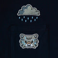 Close-up of embroidered tabby cat in rain above the pocket on dark navy tee—cute animal design for furry clothing.