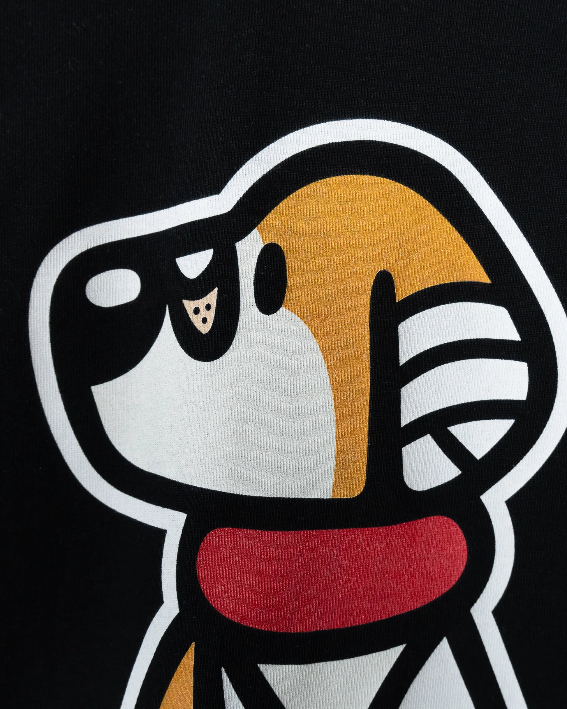 Close-up detail of the playful dog character graphic printed on a black t-shirt from the That's Ruff! collection. Bold lines and vibrant colors bring this signature design to life.